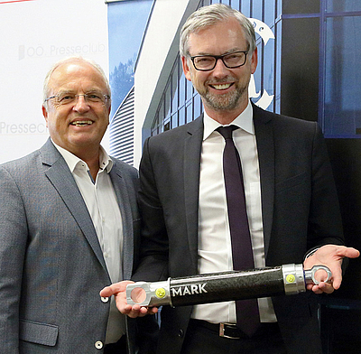 Firmenchef Rudolf Mark und Wirtschafts-Landesrat Dr. Michael Strugl präsentieren einen ultraleichten Hydraulikzylinder.